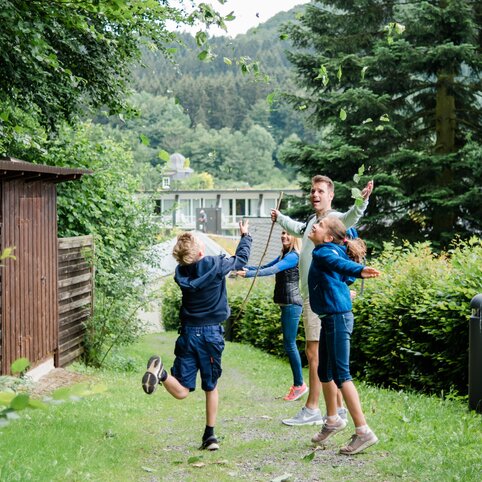 Ein Vater und seine drei Kinder beim Spielen im Grünen