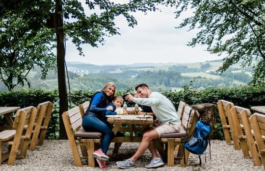 Eine vierköpfige Familie macht ein Selfie im Biergarten 