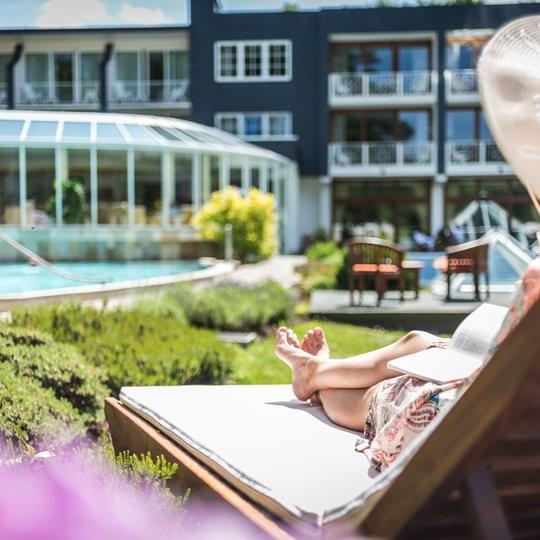 Eine Dame liegt mit ihrem Sonnenhut auf einer Sonnenliege im Wellnesshotel Deimann in NRW 