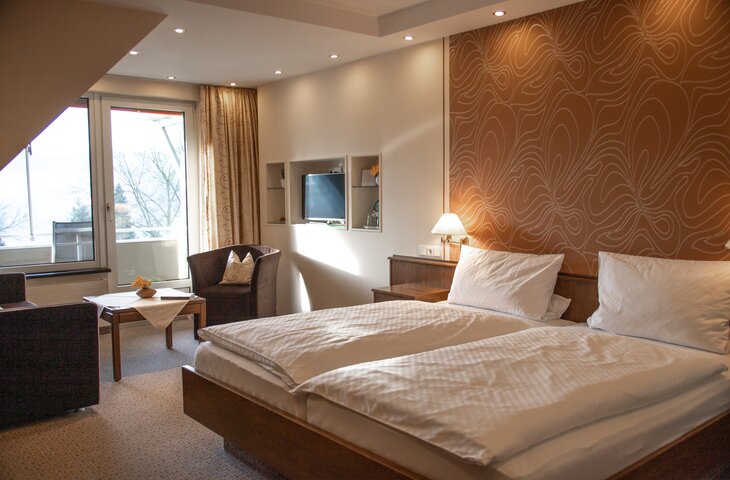 Hotelzimmer mit Doppelbett, Sitzecke, TV und Balkonblick
