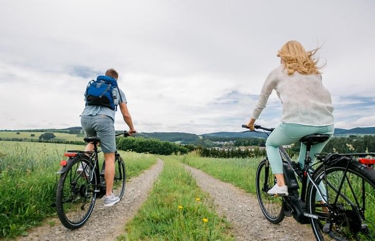 Ein Paar im Urlaub im Sauerland beim Radfahren. Im Hintergrund ist ein Wald.